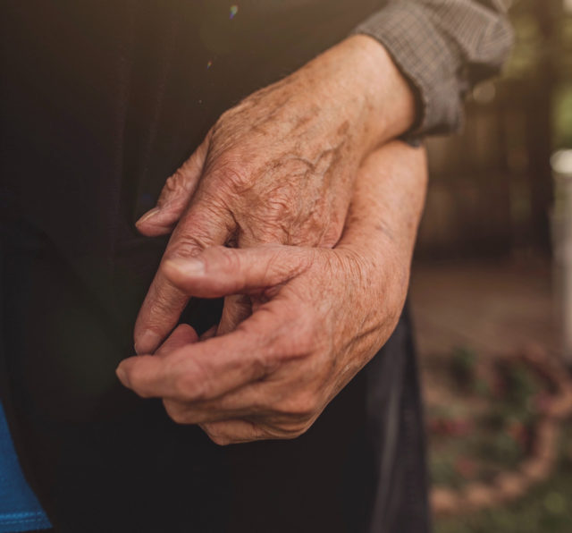 Two elderly hands holding each other.