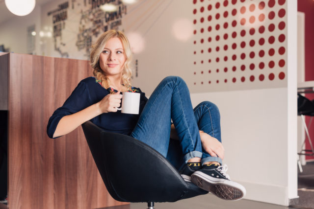 Female sitting in a chair with a coffee mug.