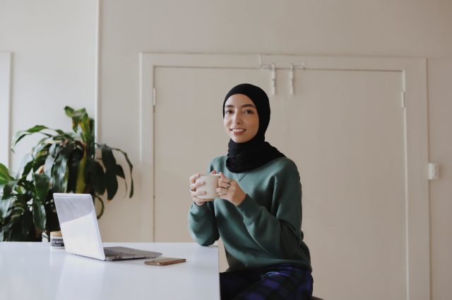 Female smiling with coffee cup at work station.